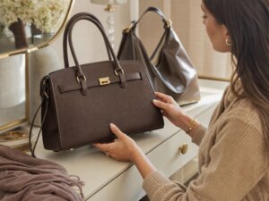 Woman inspects the structure and hardware of an elegant unbranded brown handbag